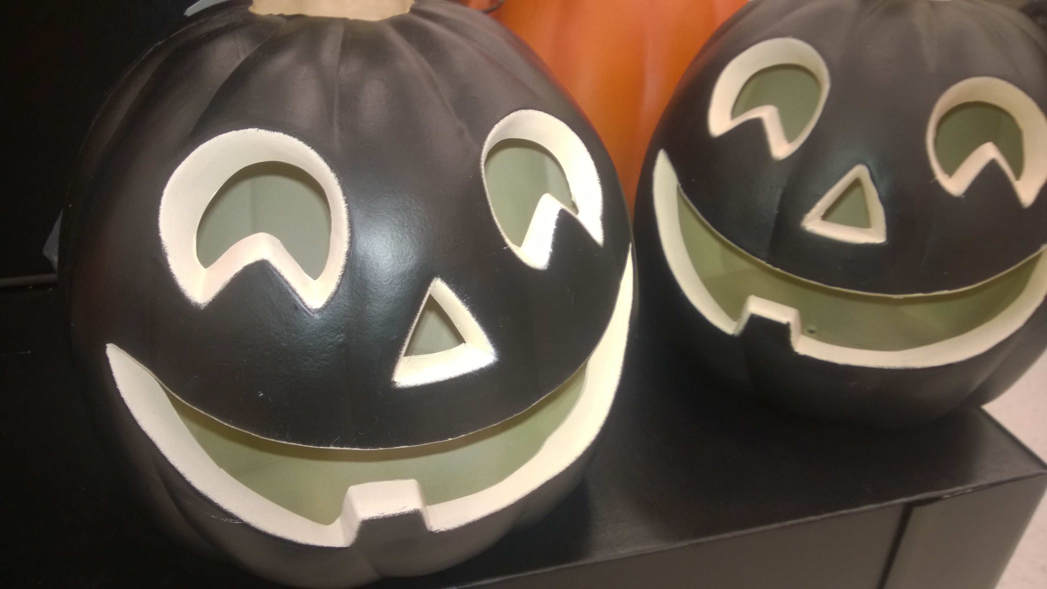 Close-up of two black jack-o’-lantern decorations with smiling faces.