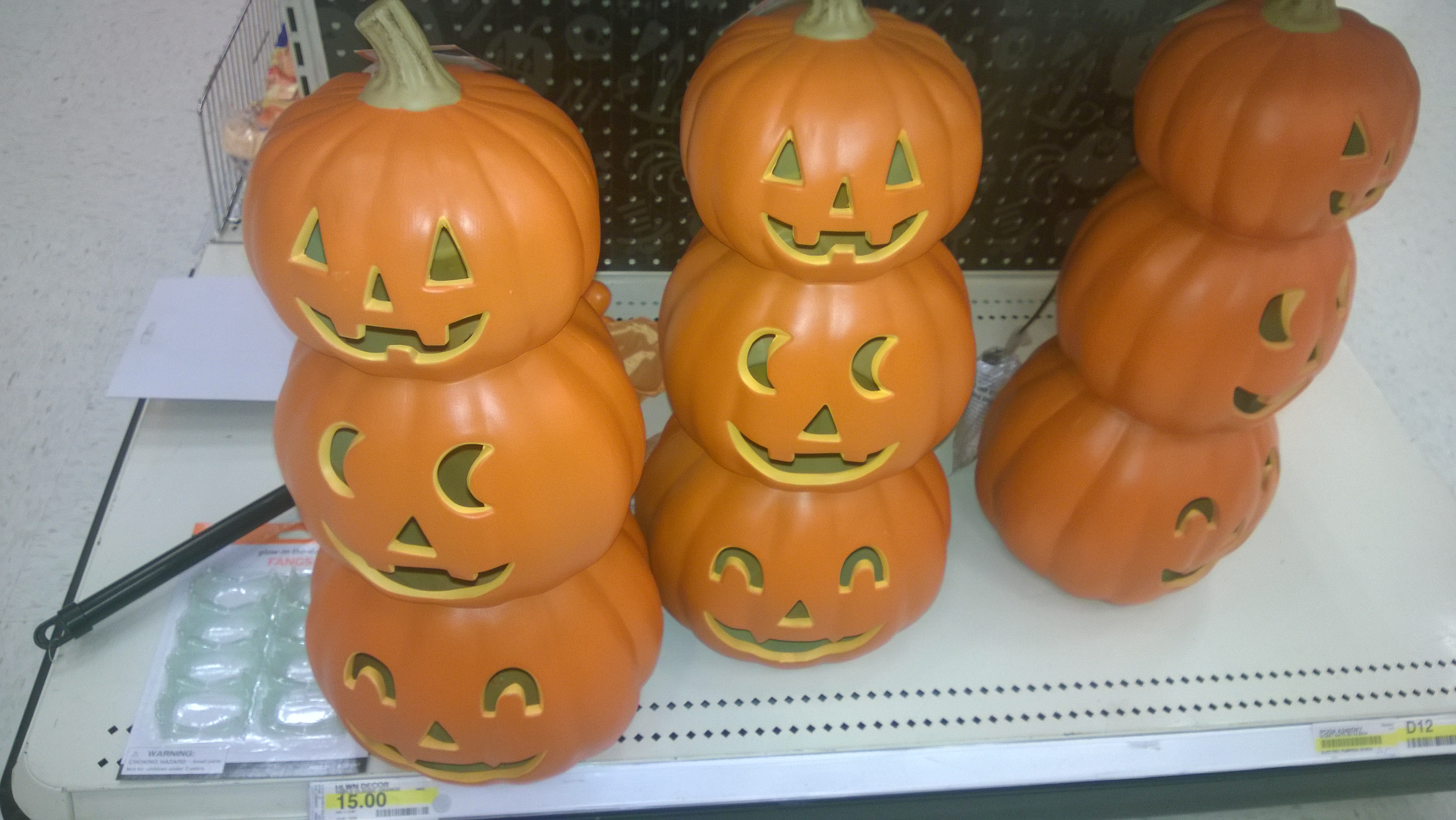 Three stacks of smiling orange jack-o’-lantern decorations on a shop shelf.
