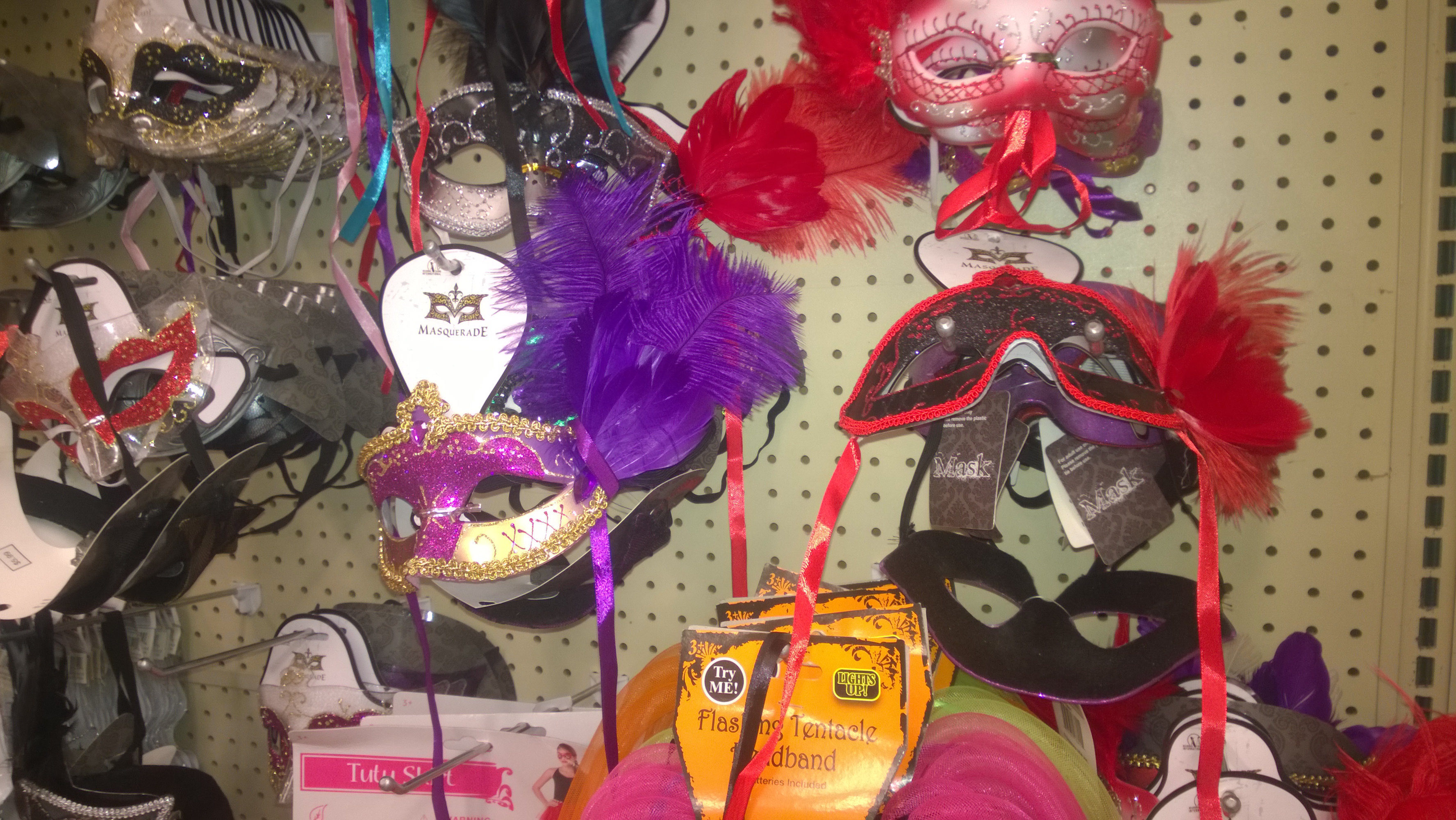 Colorful feathered masquerade masks hanging on a shop display.