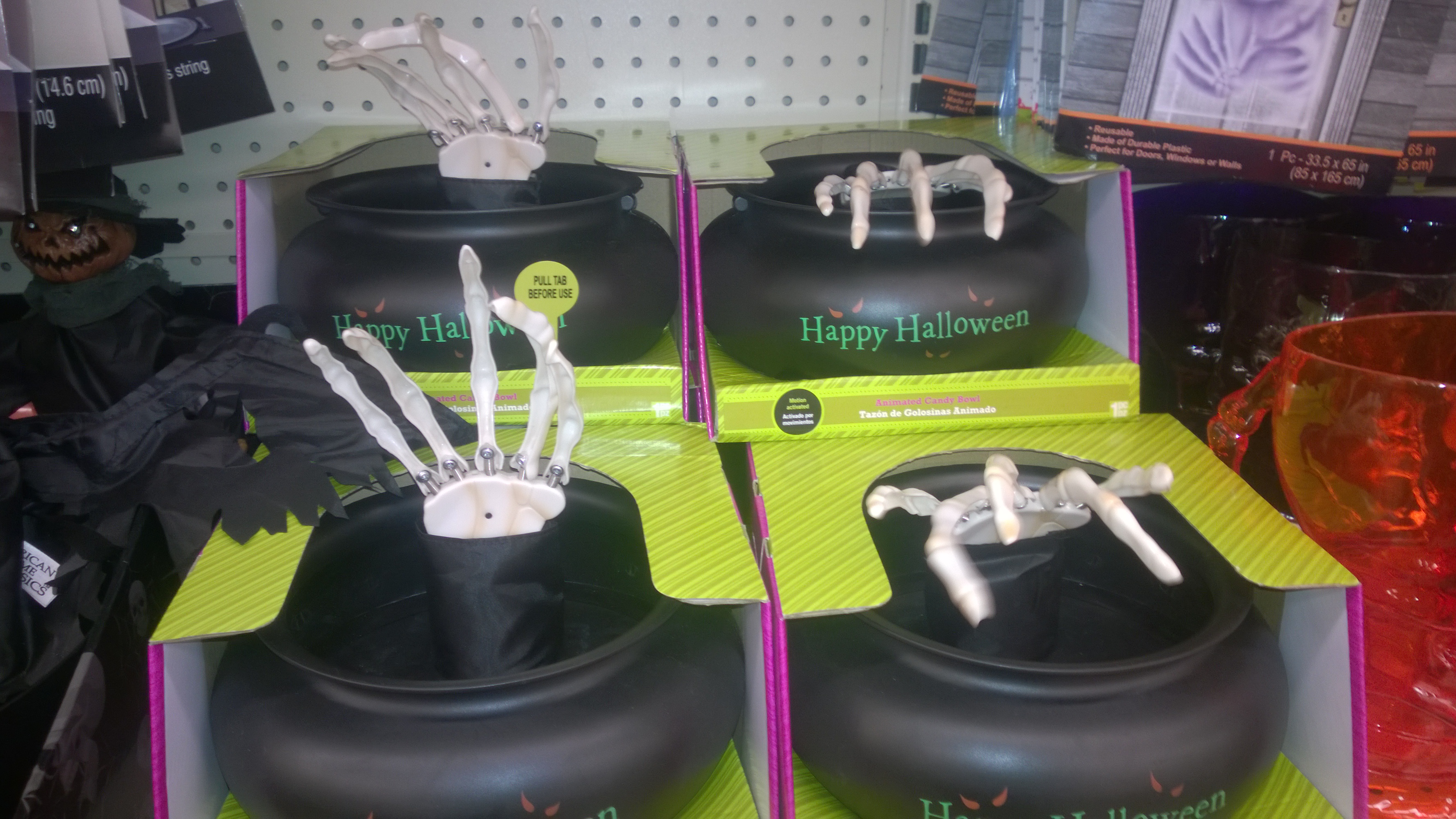 Black Halloween candy bowls with reaching skeleton-hand decorations on a store shelf.