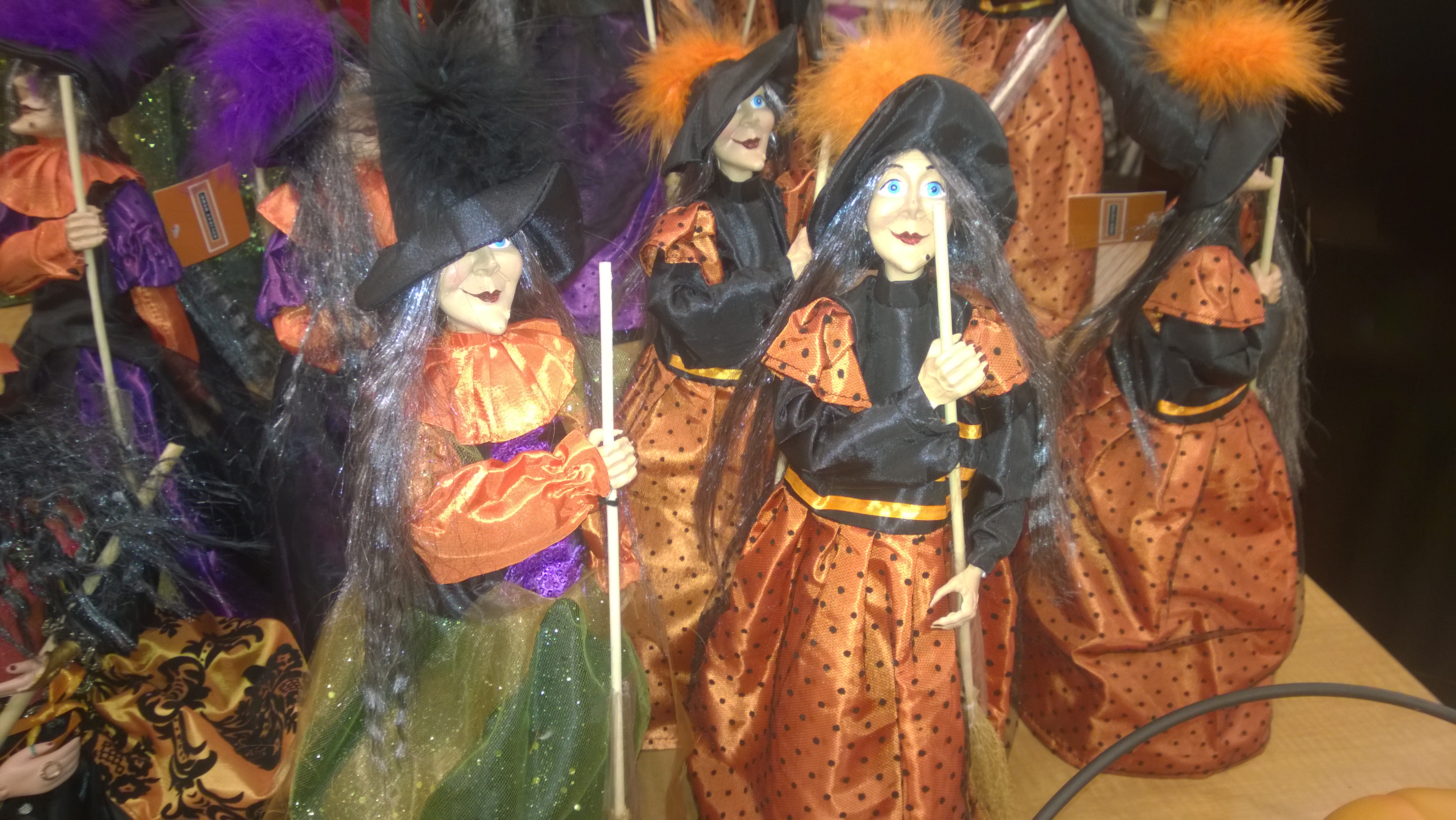 Decorative witch figures in pointed hats and colorful dresses on a shop display.
