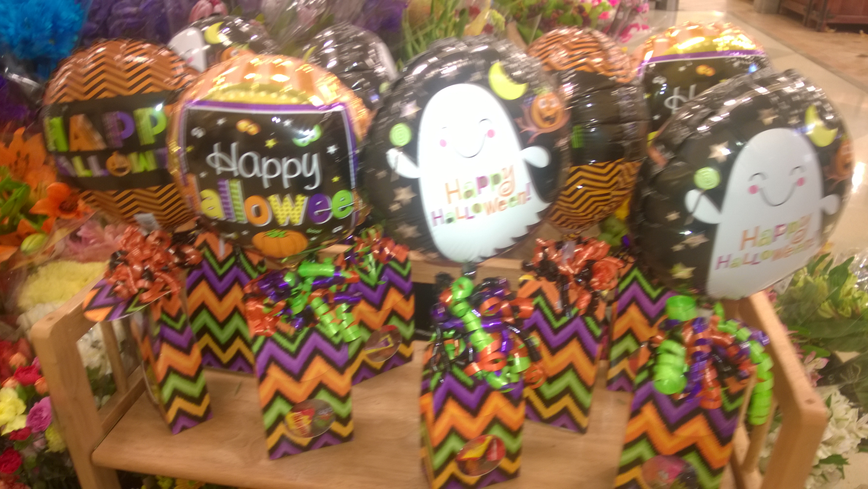 Colorful Halloween foil balloons above chevron-patterned gift bags on a shop display.